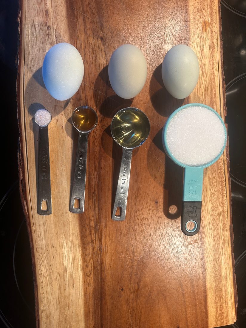 Eggs, salt, vanilla, oil and sugar measured out on a wooden board